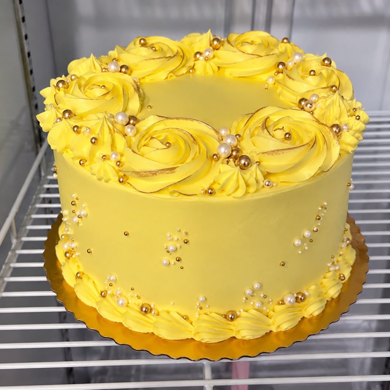 Yellow buttercream cake with rosettes and gold and pearl sprinkles